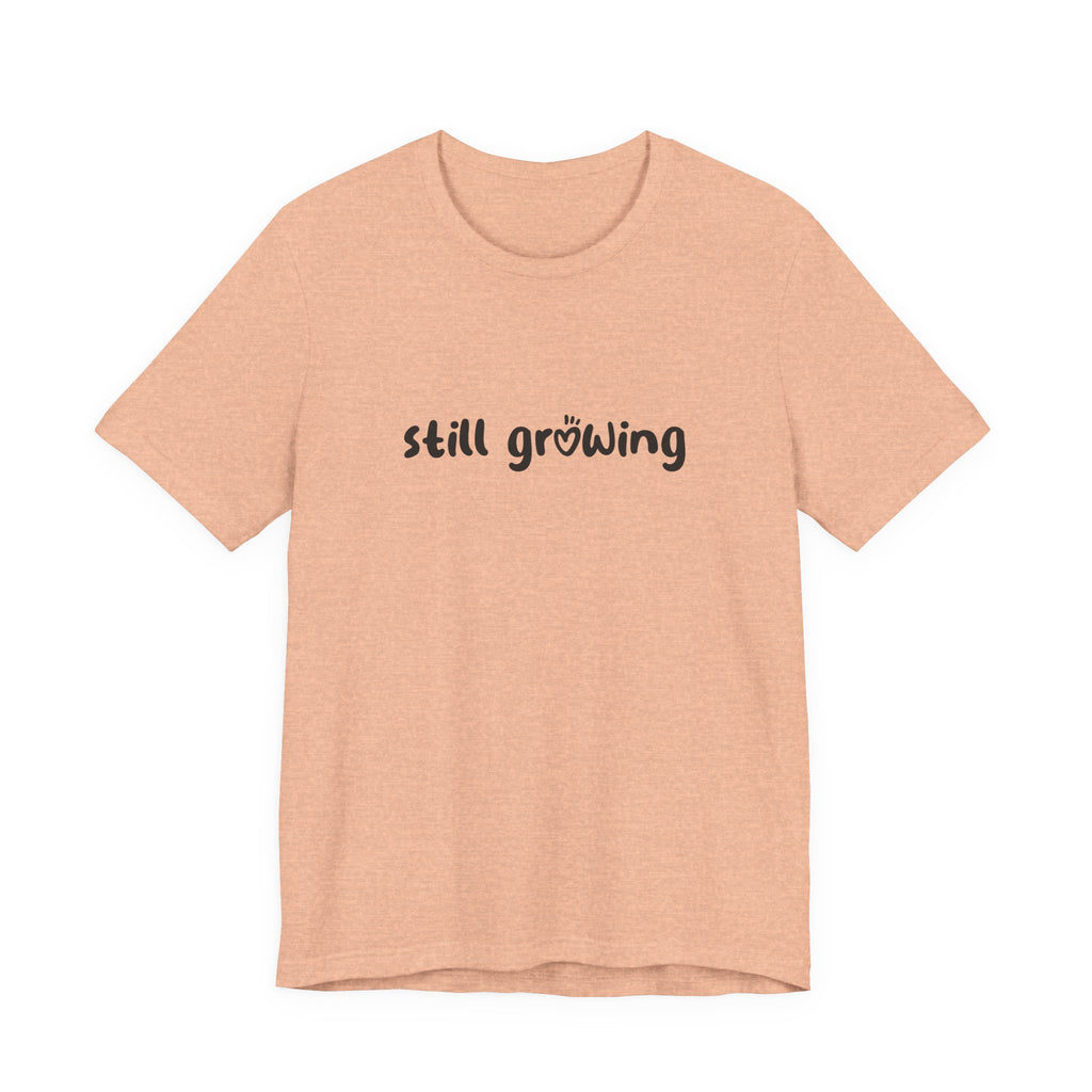 Beige t-shirt with 'still growing' text on a white background