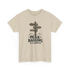 Beige t-shirt with mountain-themed graphic and text 'peak bagging is a lifestyle' on a white background