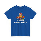 Blue t-shirt with a sports graphic of a cartoon character and text 'it looked easier on TV' on a white background